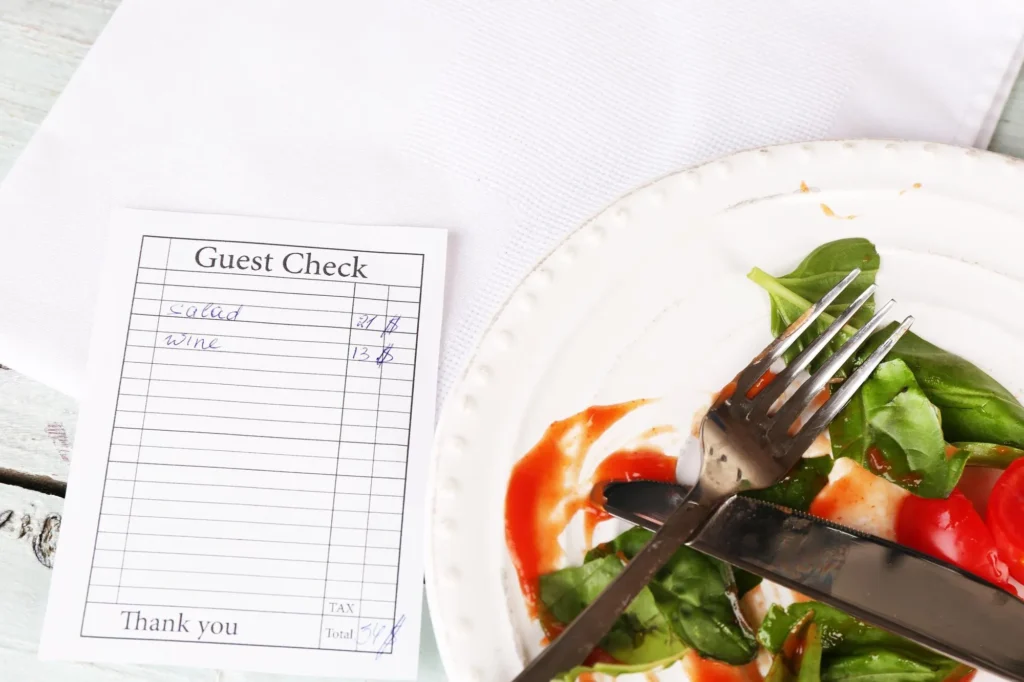 Guest check beside a partially eaten salad