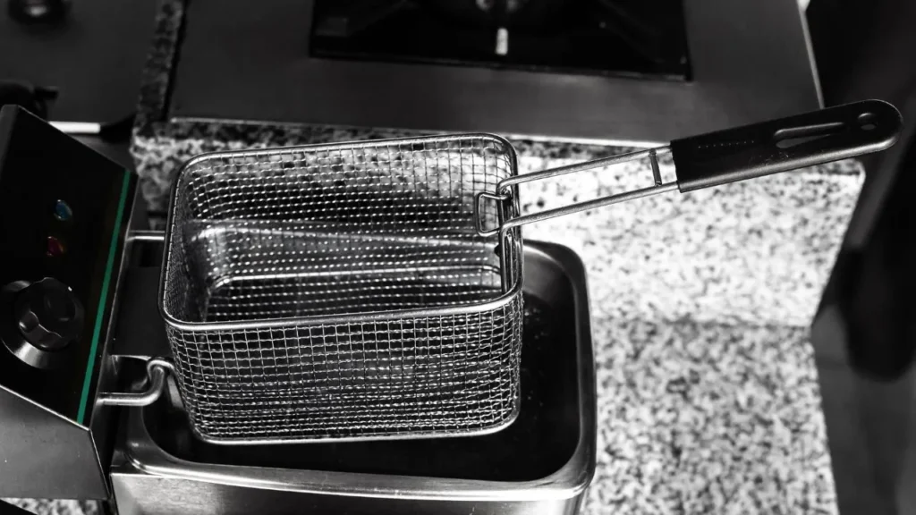 A clean deep fryer basket with handle on granite counter