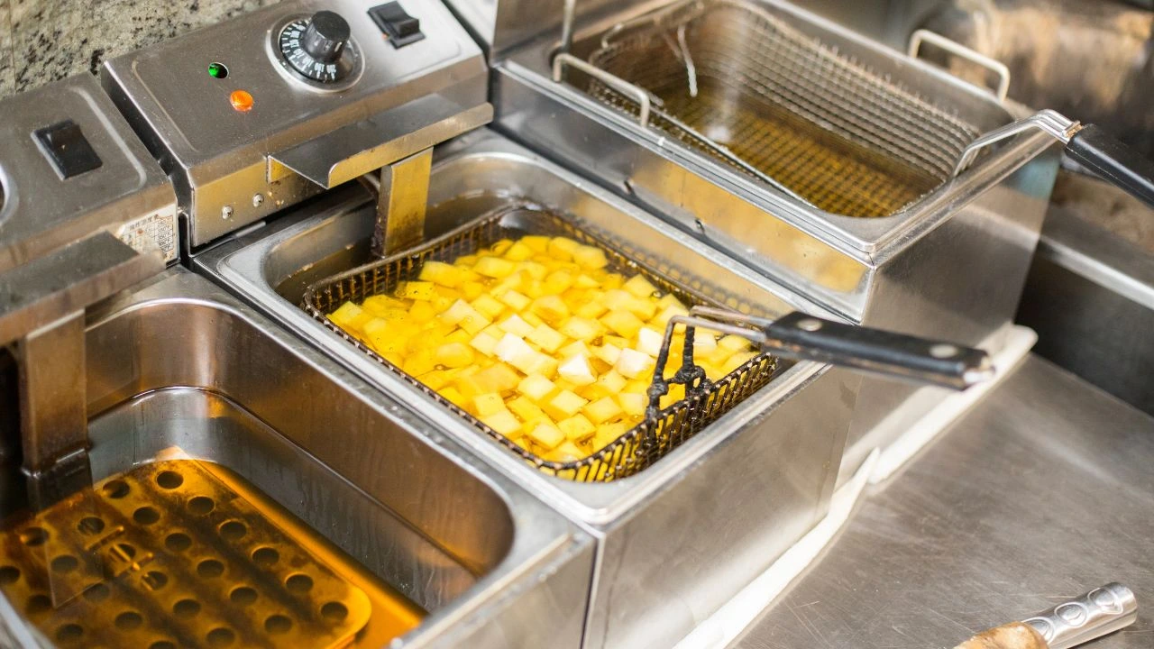 Fryer with oil and diced potatoes being cooked