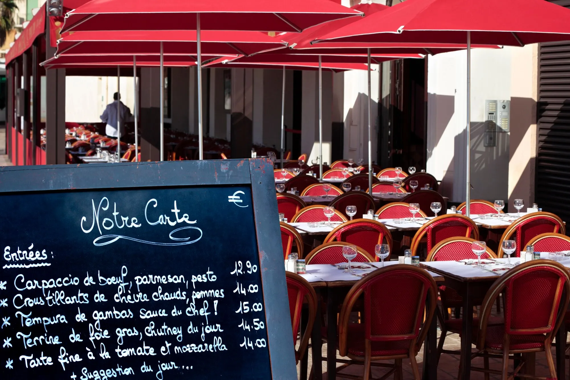 Outdoor restaurant seating with menu board on display.