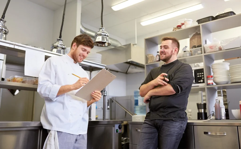 Two chefs collaborating and writing on clipboard.