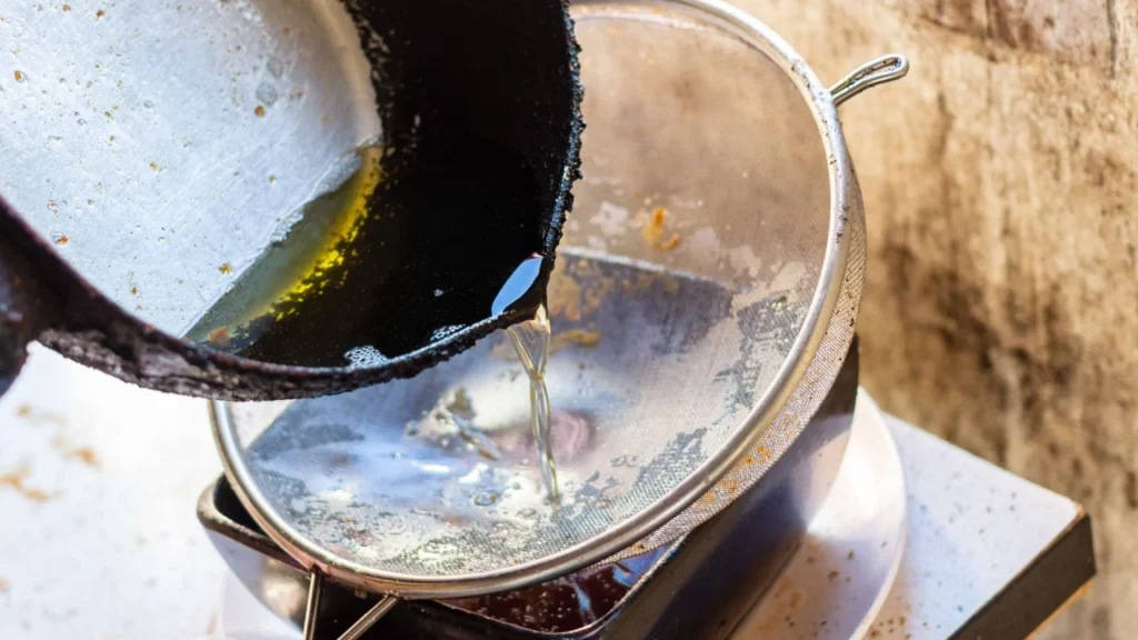Used cooking oil being strained through a mesh colander