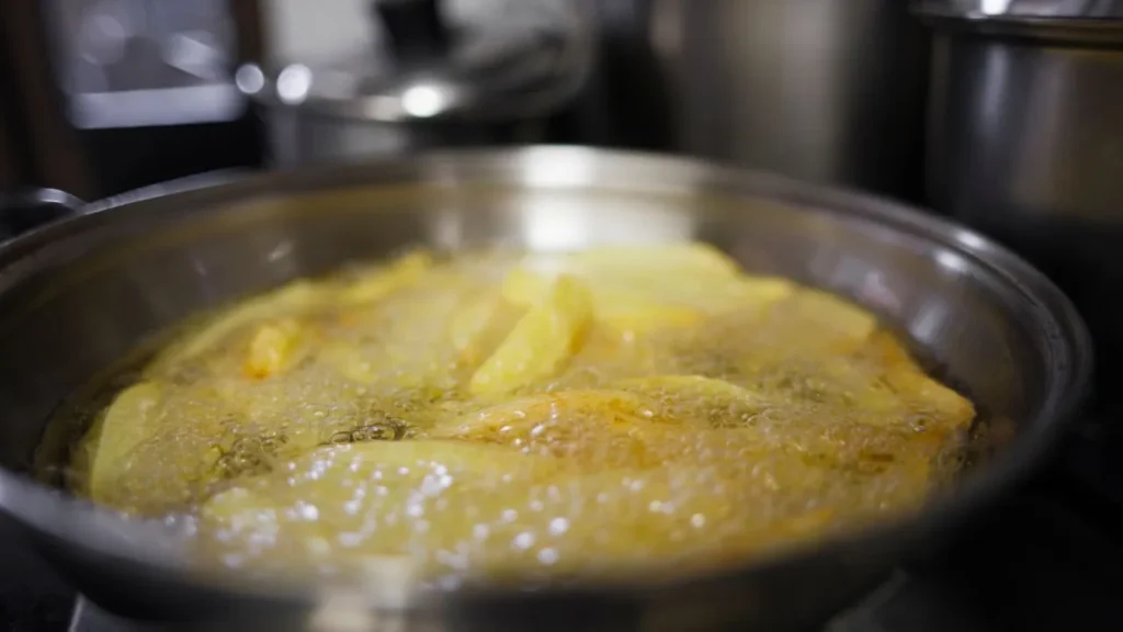 Frying potatoes in pan with steam rising.