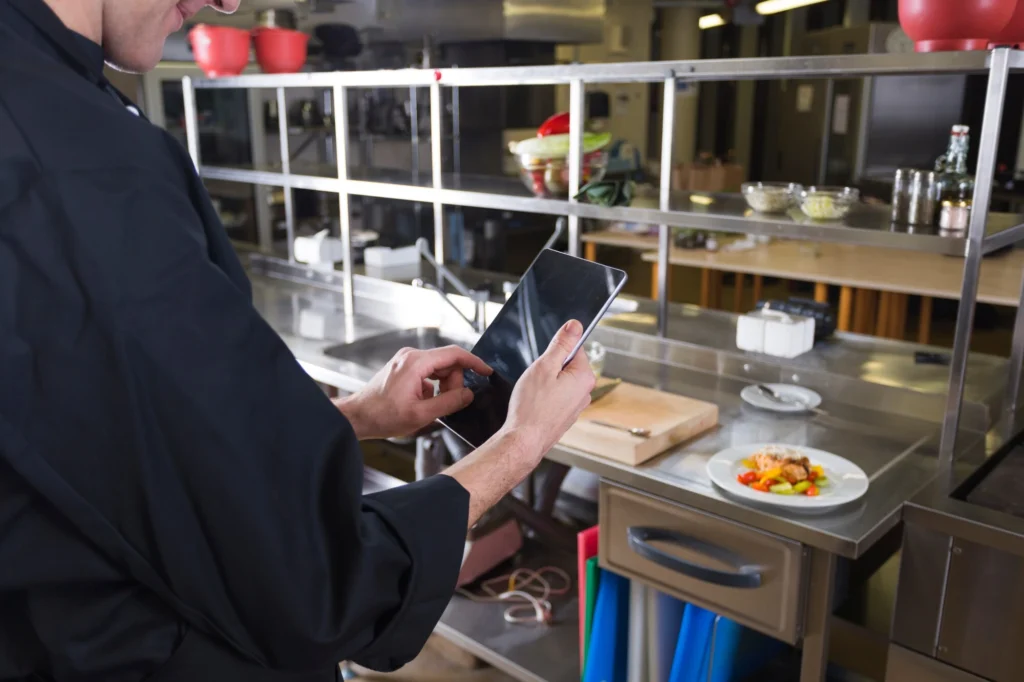 Chef using tablet in kitchen for preparation.