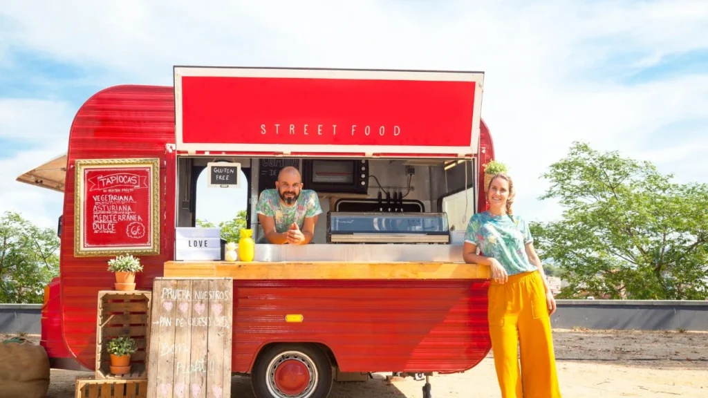 Smiling vendors at a branded vibrant red street food truck