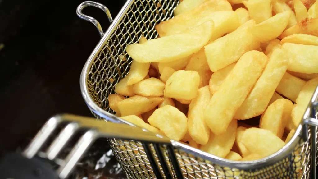 Golden crispy fries in a deep fryer basket.