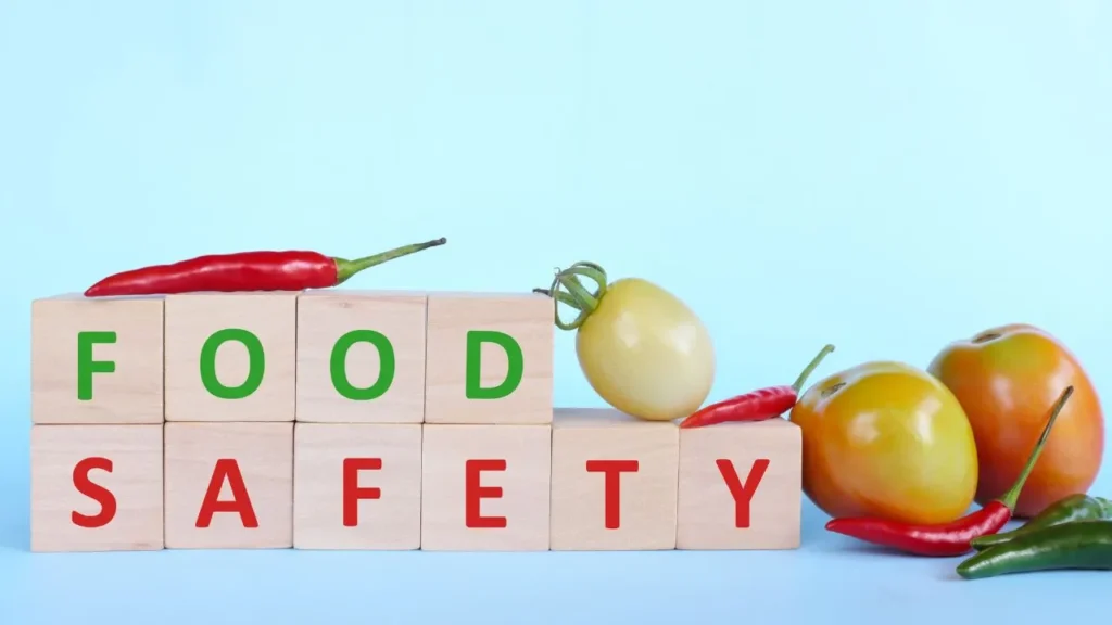 Tomato and wooden blocks with word safe food on blue background with copy space.