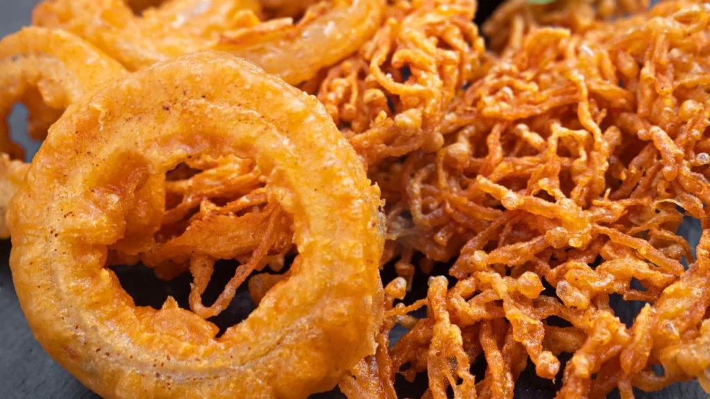 Crispy golden fried onion rings and shredded fried vegetables close-up.