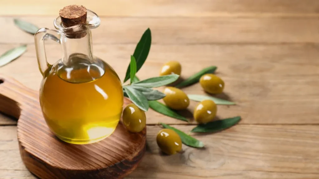 Glass bottle of olive oil with fresh olives.
