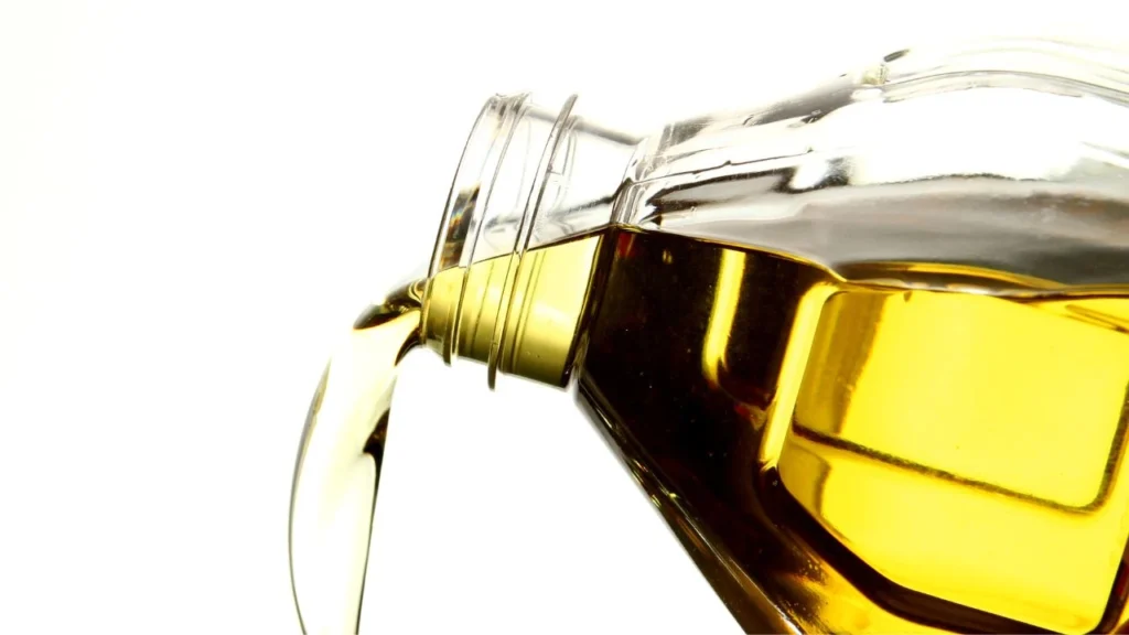 Golden cooking oil pouring from glass bottle