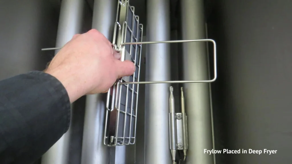 Hand placing Frylow device into commercial deep fryer