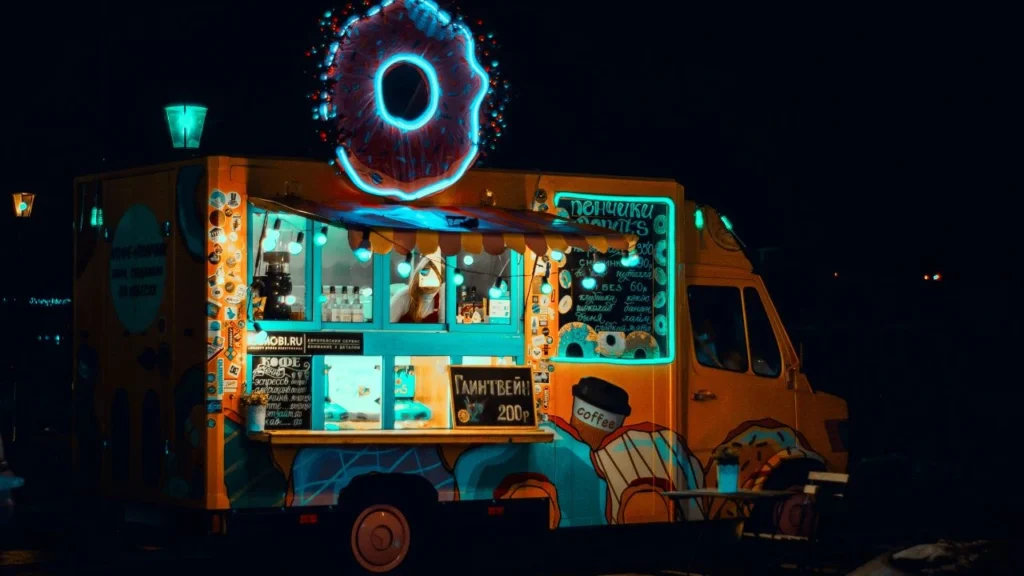 Colorful donut-themed food truck glowing at night.