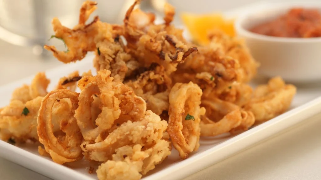 Crispy calamari on white plate with marinara sauce