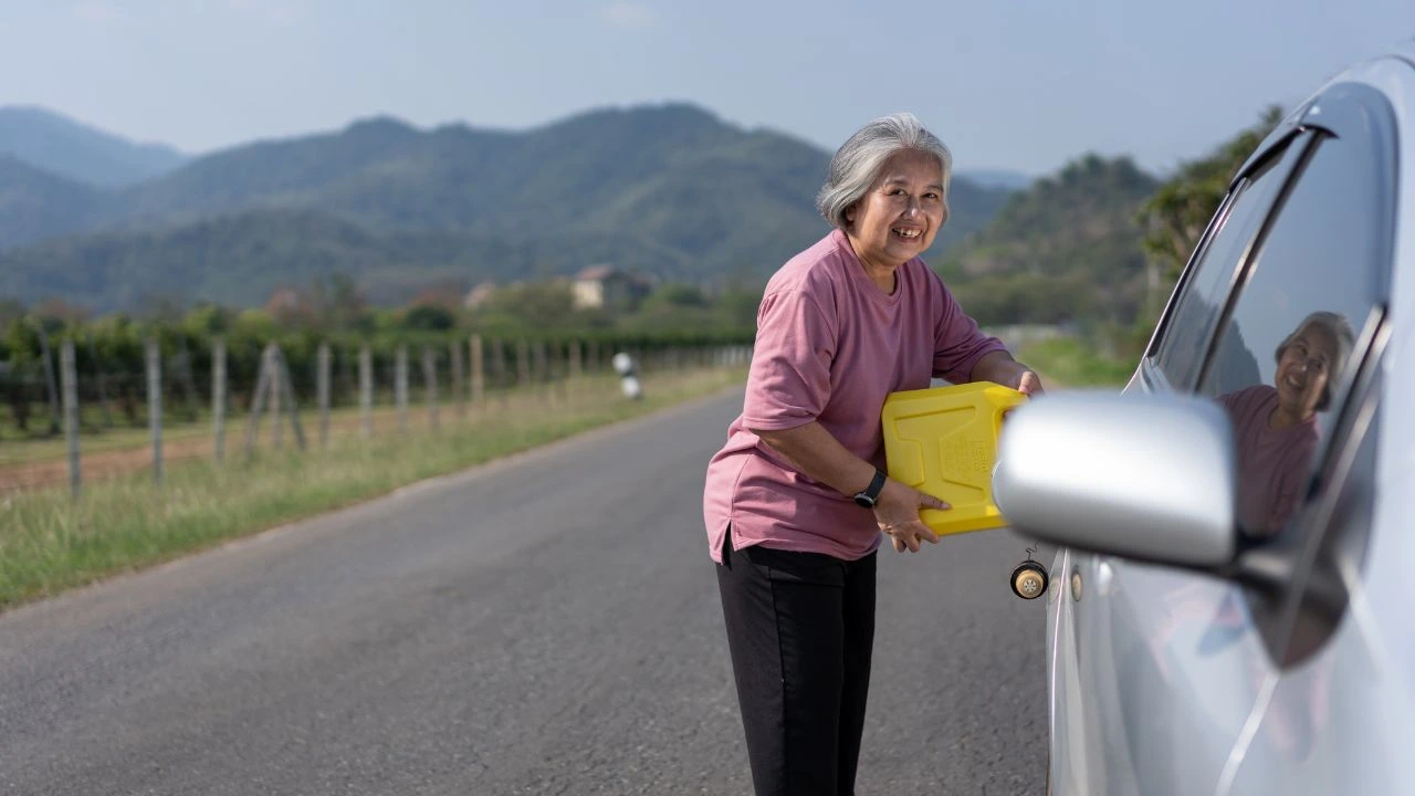 A woman uses a spare gallon of gas to fuel car