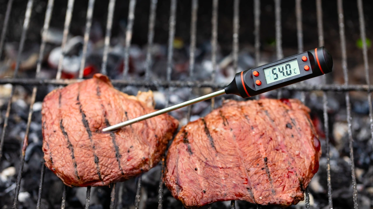 Medium rare steak on bbq with digital probe thermometer