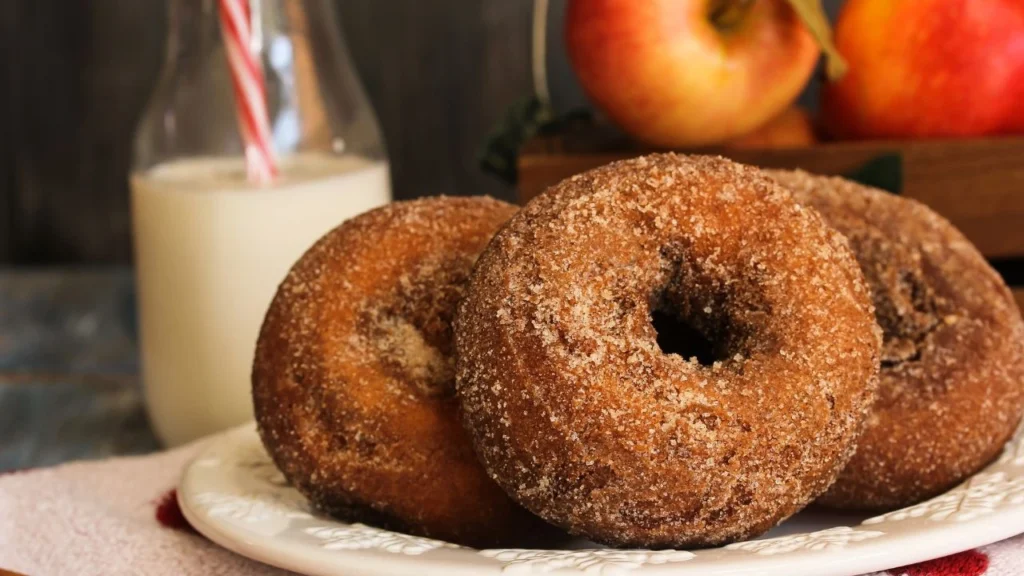Fresh apple cinnamon donuts on a plate with milk.