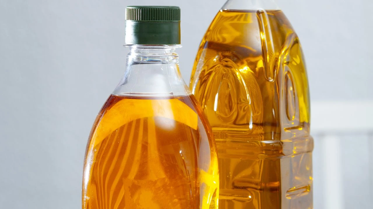 Two bottles including canola oil vs peanut oil with green cap.