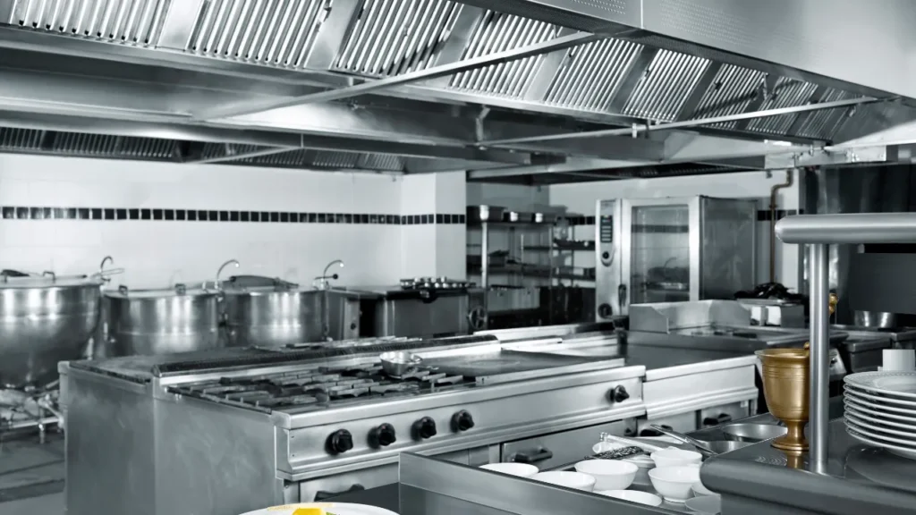 Modern commercial kitchen setup with stainless steel appliances and ventilation.