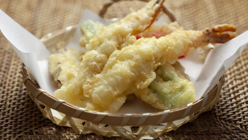 Crispy shrimp tempura and vegetables served in a woven basket.