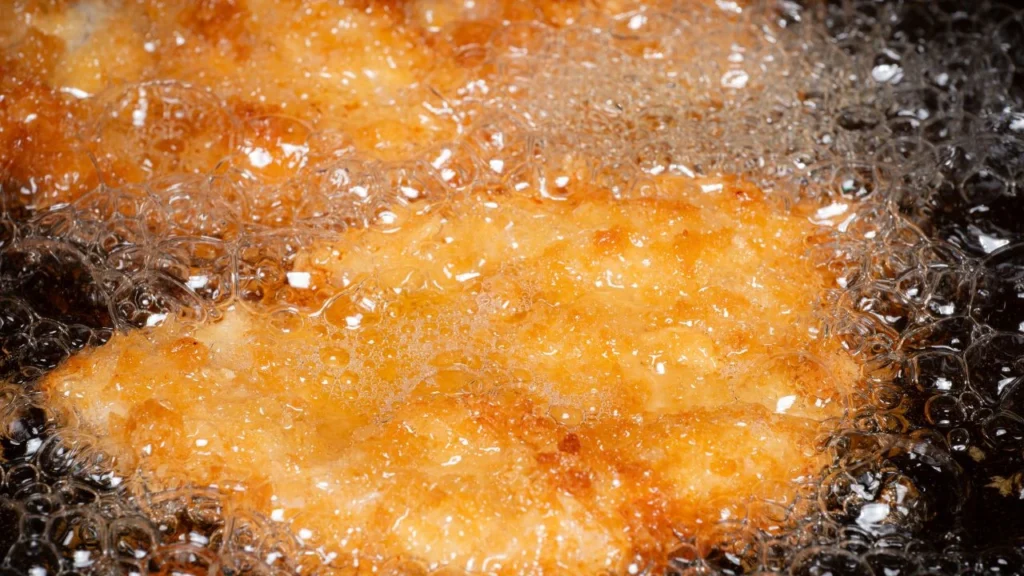Golden fried food bubbling in oil, showing excessive foam formation