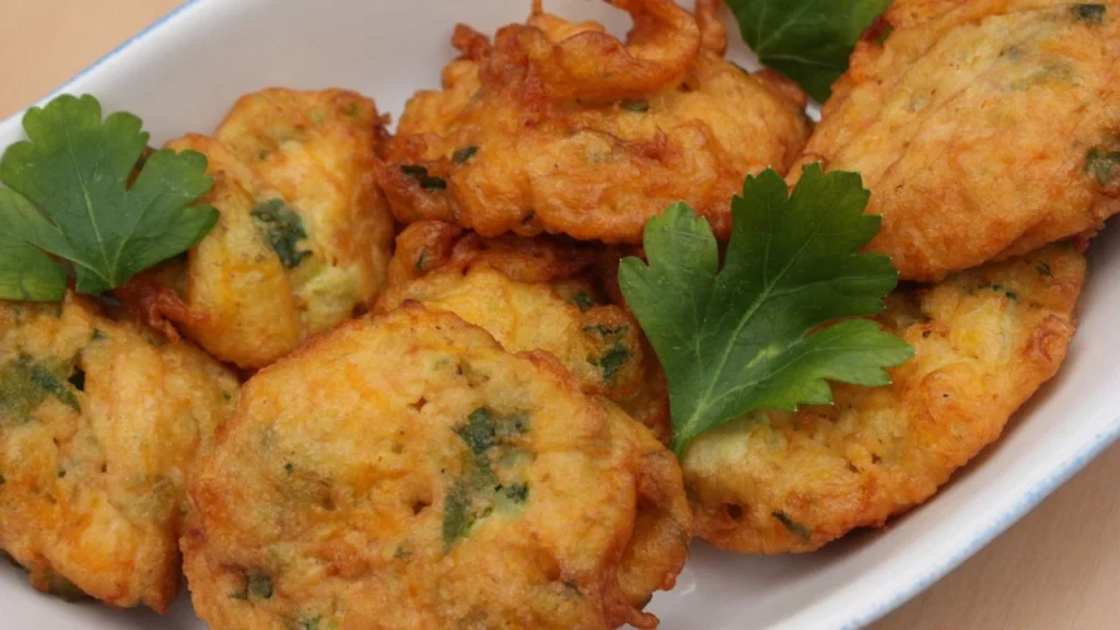 Golden zucchini fritters garnished with fresh parsley on a plate.