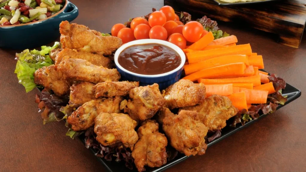 Crispy chicken wings served with carrots, tomatoes, and sauce.