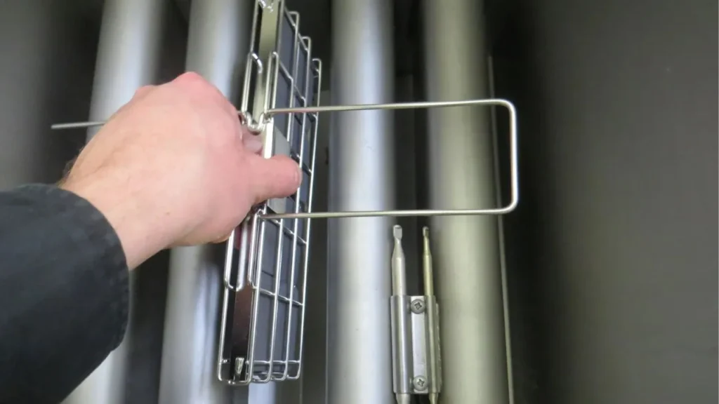 Hand placing Frylow device inside fryer for oil optimization.