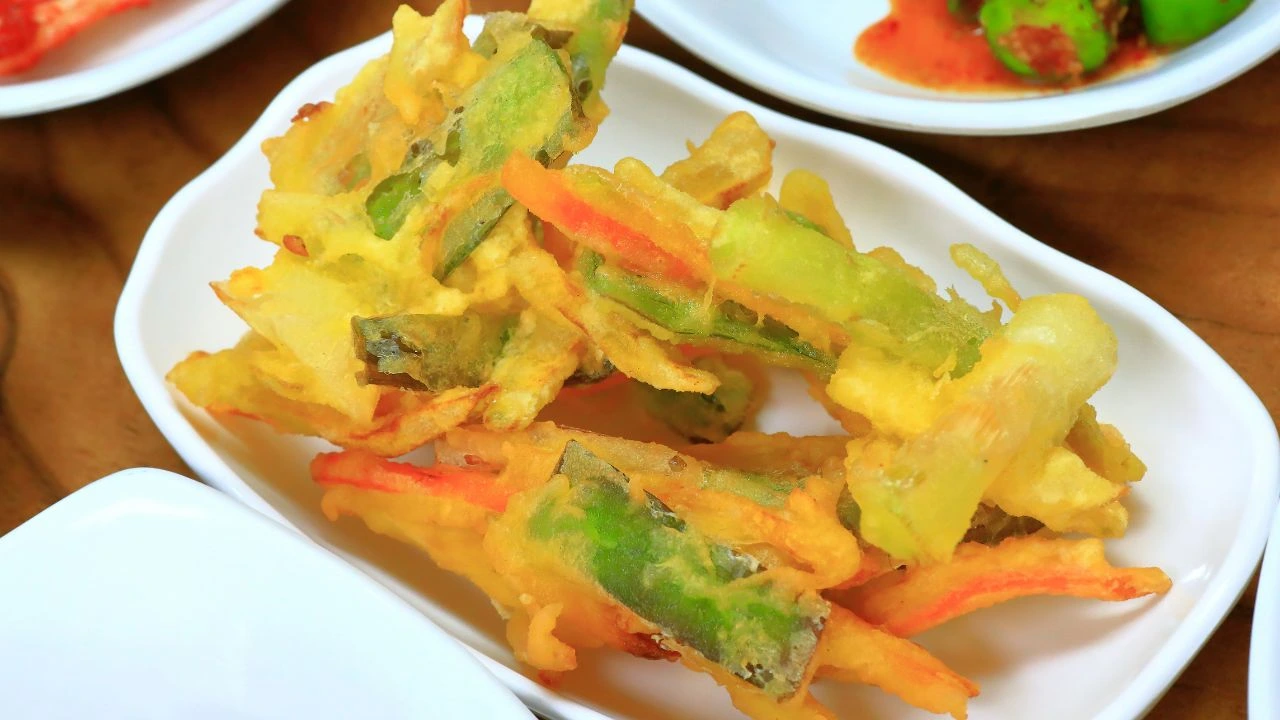 Crispy vegetable tempura served in a white ceramic dish.