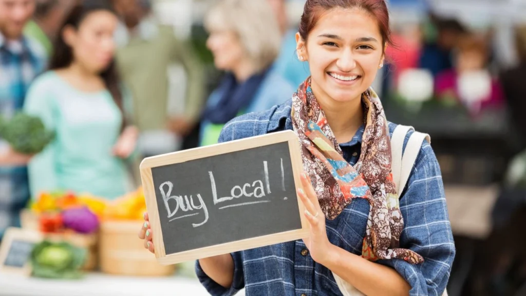 Woman holds sign encouraging customers to buy local ingredients.