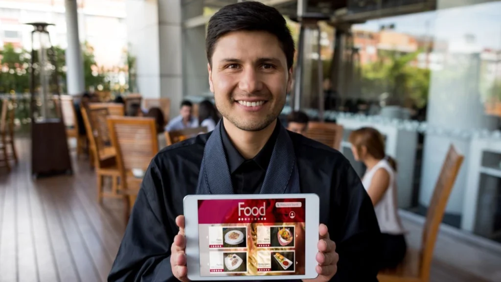 Restaurant server displays digital menu on tablet for ordering.