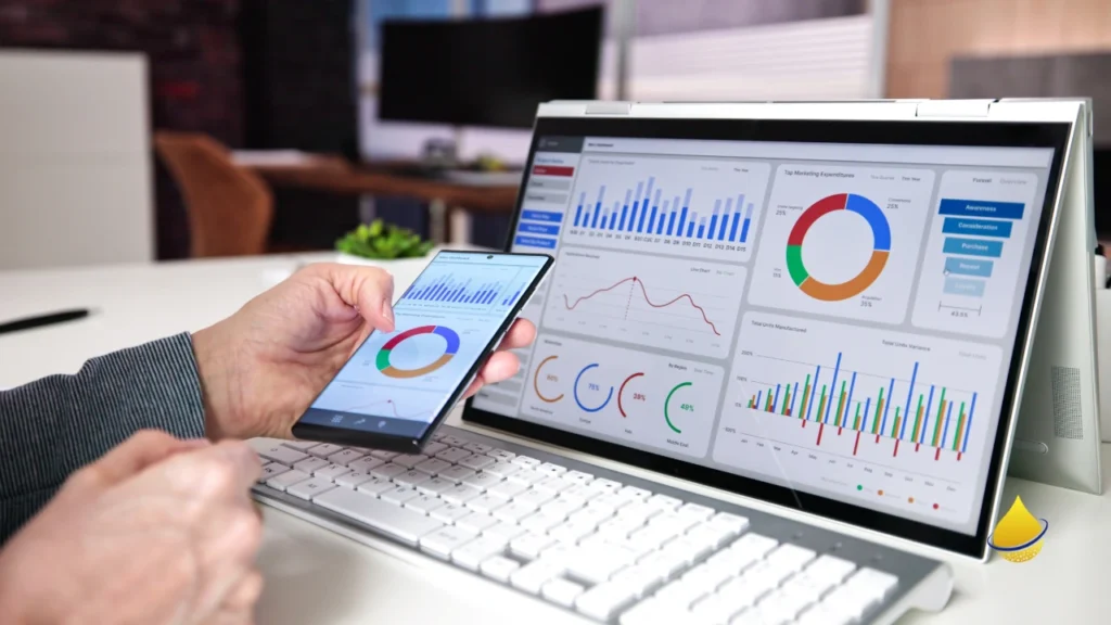 Person analyzing real-time data on smartphone and desktop screen.