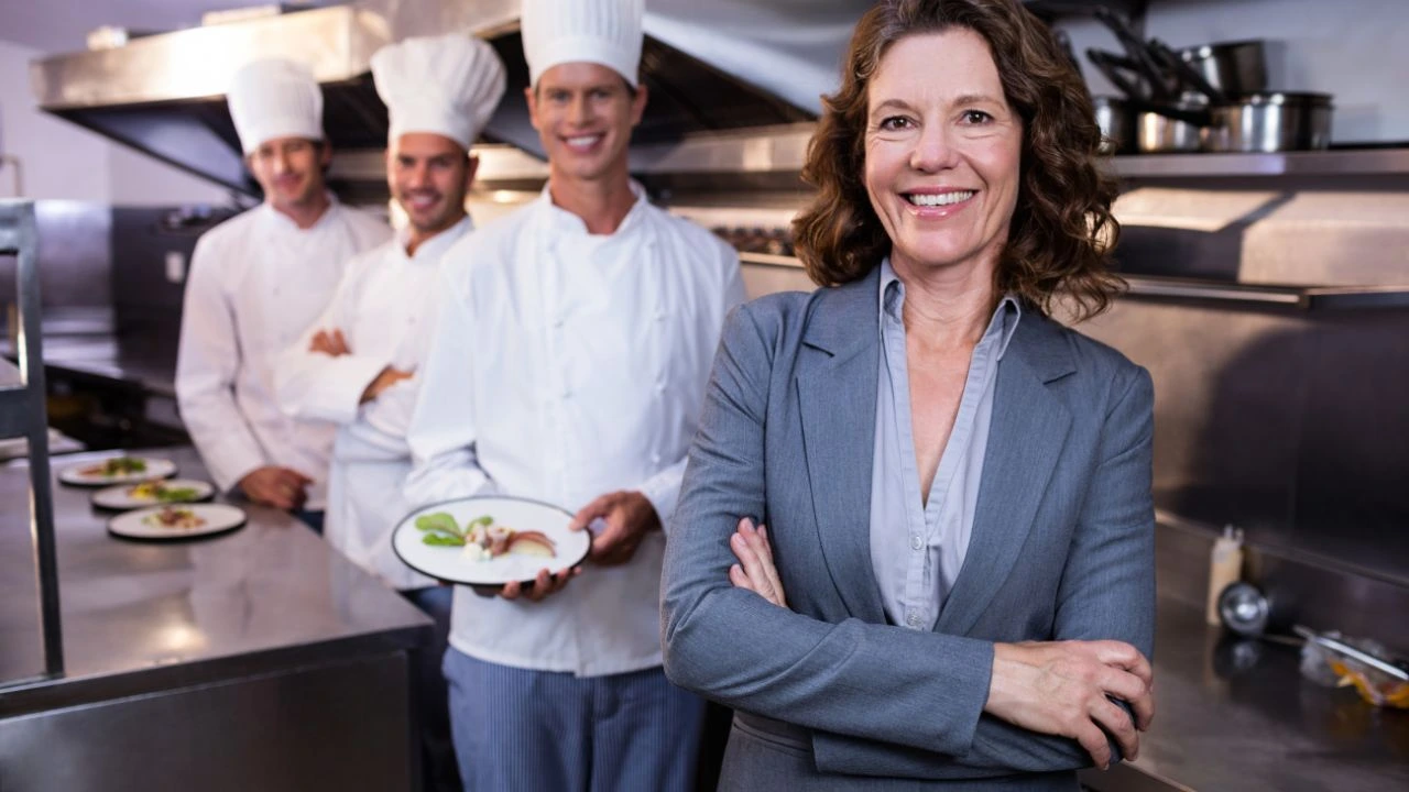 Restaurant leader standing in front of team of chefs smiling at camera