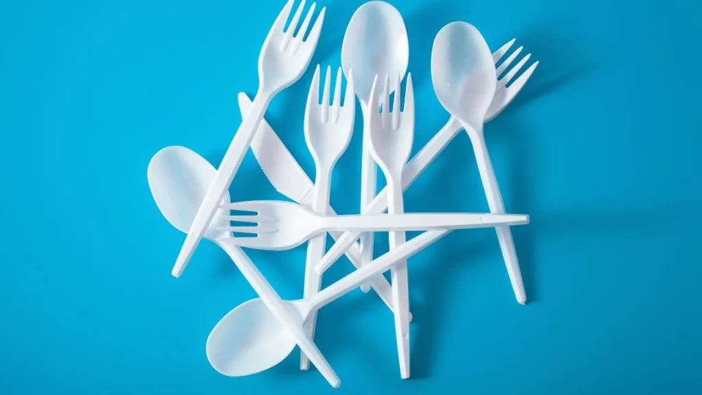 Pile of white single-use plastics on blue background.