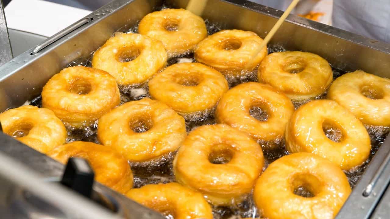 doughnuts frying in oil in commercial kitchen