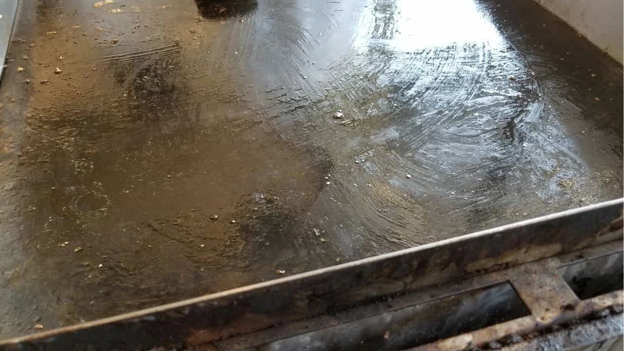 Dirty stainless steel griddle in commercial kitchen