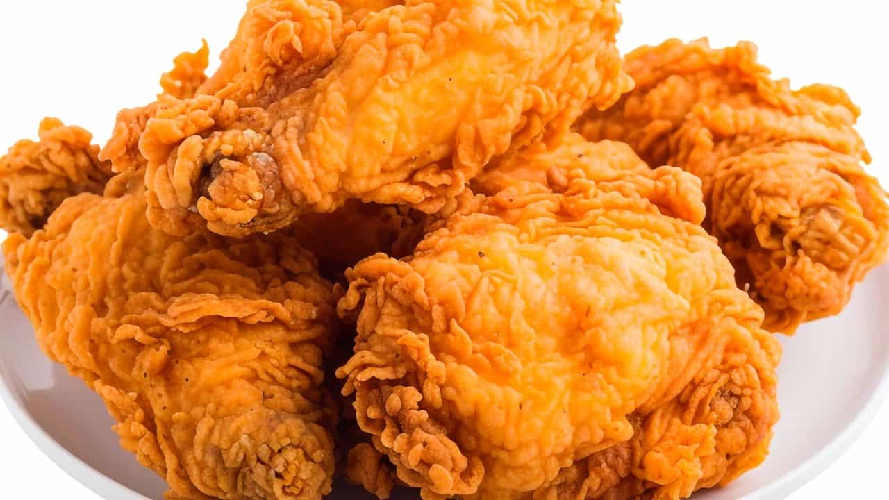 Crispy golden fried chicken pieces on white plate.