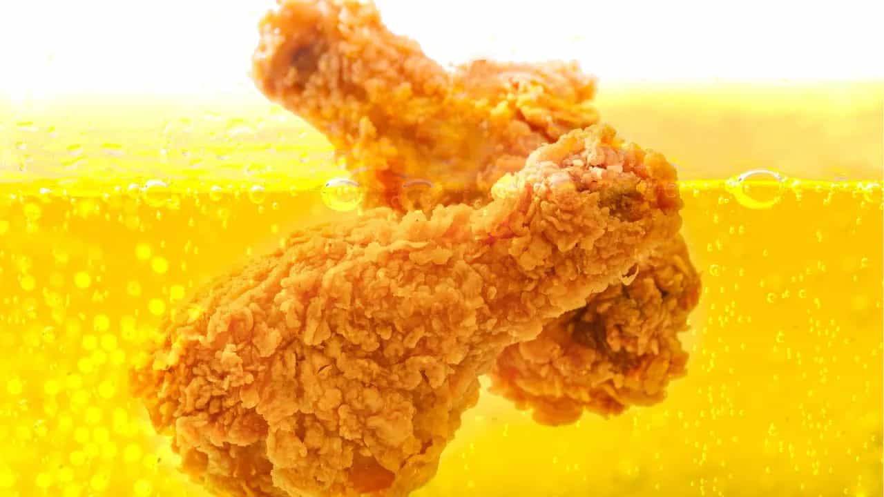 Crispy fried chicken submerged in hot golden fry-oil.