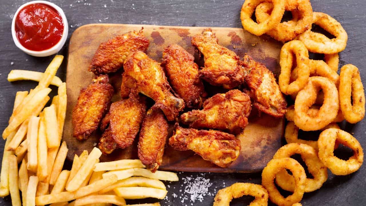 Fried foods and ketchup on a wooden cutting board