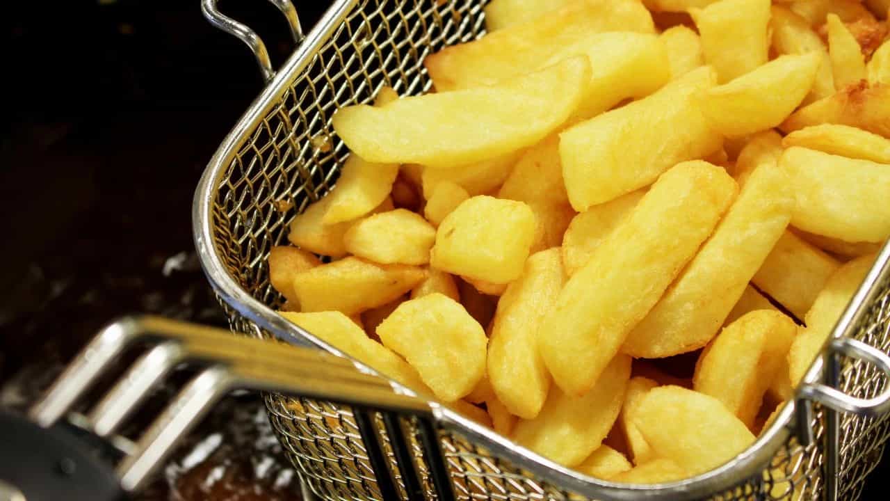 Cooking french fries in a deep fryer basket.