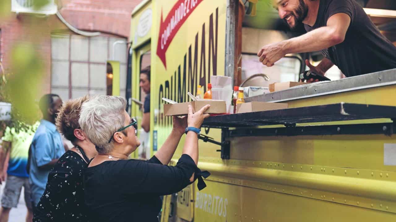 Customers receiving food from a yellow food truck business