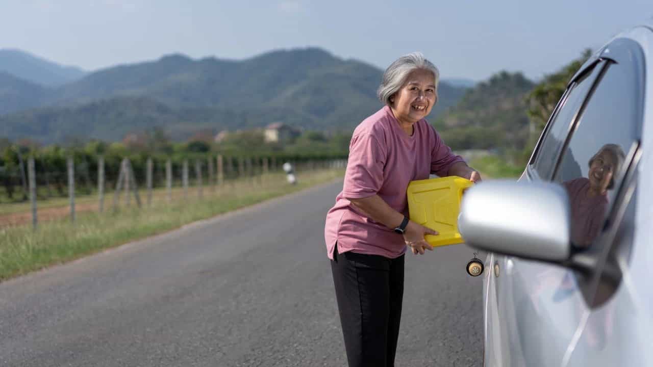 A woman uses a spare gallon of gas to fuel car